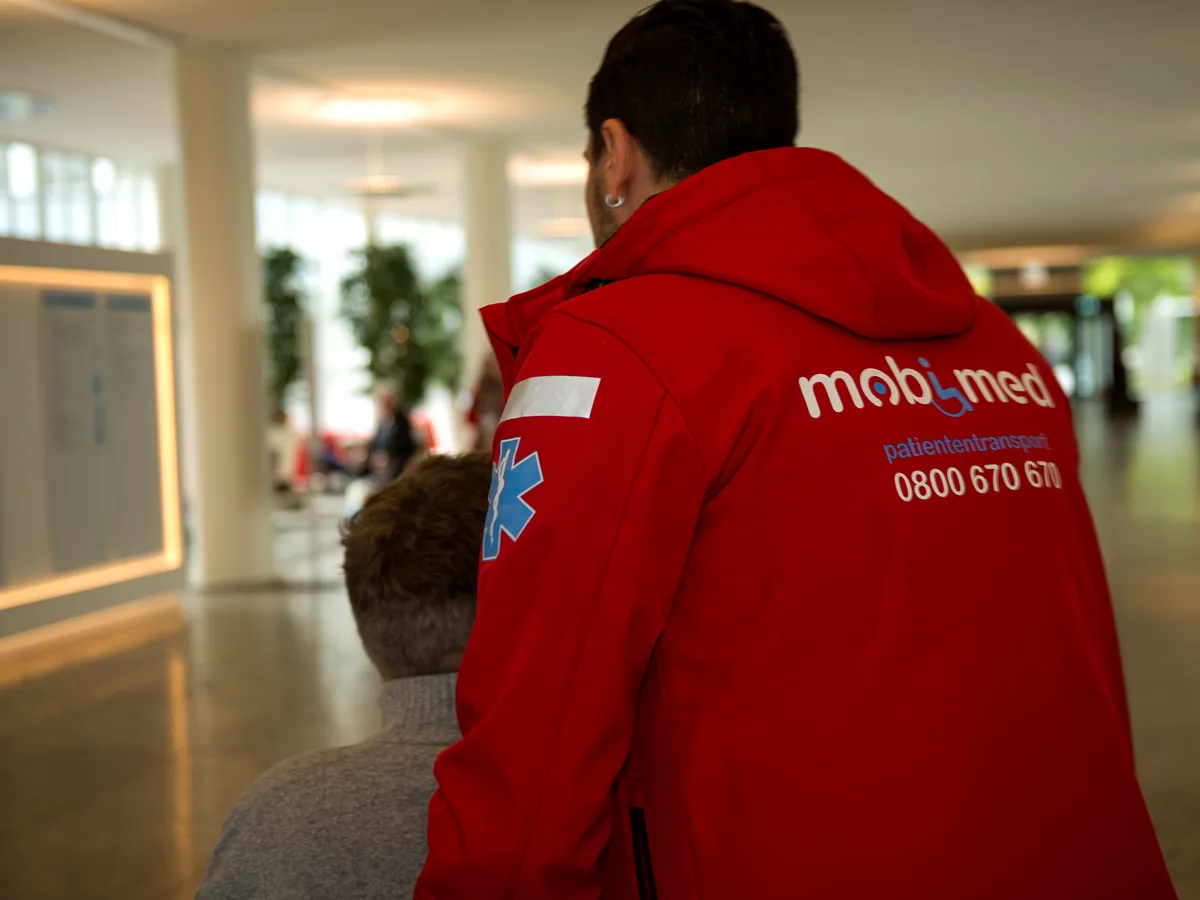 Mobimed-Mitarbeiter begleitet eine Patientin durch die Eingangshalle eines Spitals