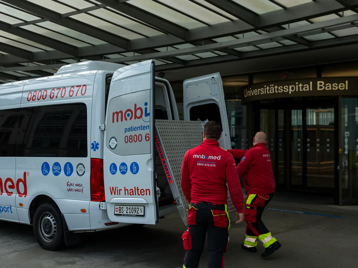 Mobimed-Team mit Fahrzeug vor dem Eingang des Universitätsspitals Basel